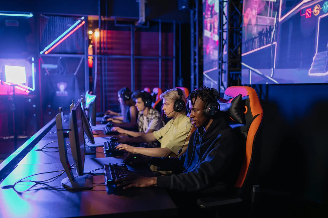 Four gamers sitting next to each other focusing on computer screen at gaming event